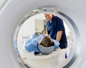 Male Doctor Looking At Female Patient Undergoing CT Scan